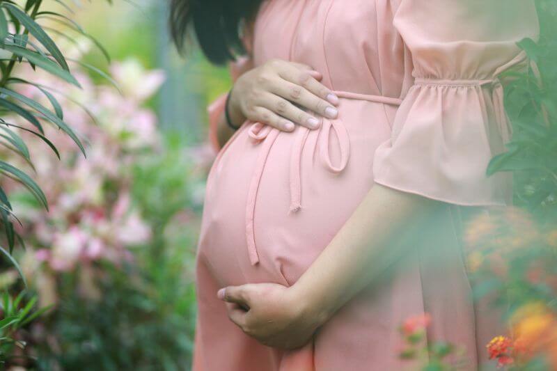 femme pendant sa grossesse avec les mains au niveau du périnée