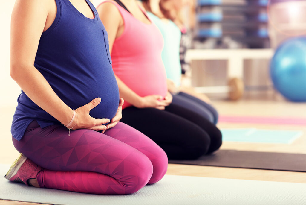 femmes enceintes en tenues de sport assises genoux pliés