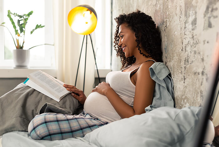 femme enceinte livre dans son lit garder un périnée tonique avant et pendant la grossesse
