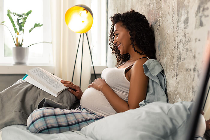 femme enceinte  livre dans son lit garder un périnée tonique avant et pendant la grossesse 