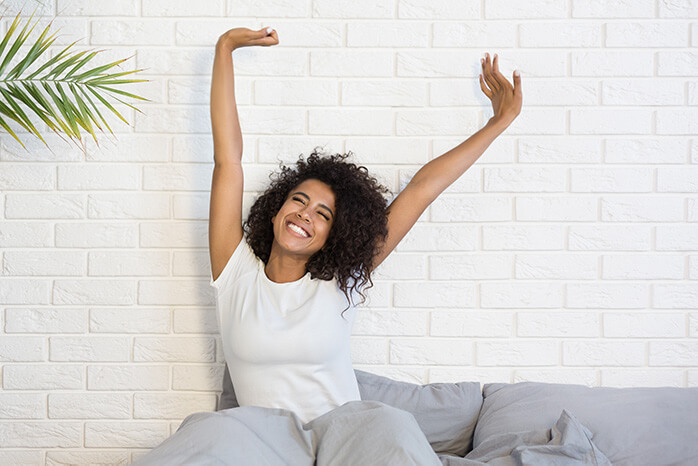 femme métisse se réveille heureuse et s'étire