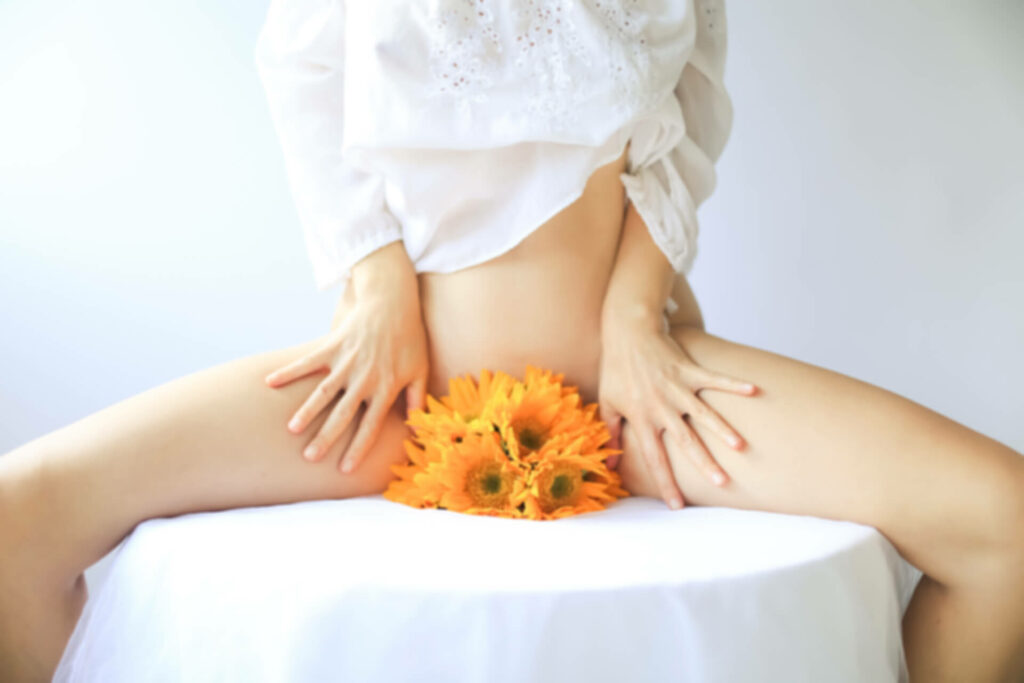 femme pose jambes écartées avec une fleur symbolise le pubis