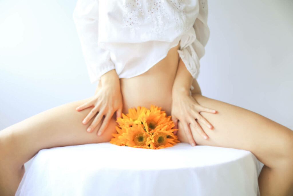 sitzende Frau mit Blumen, die die Vagina verdecken