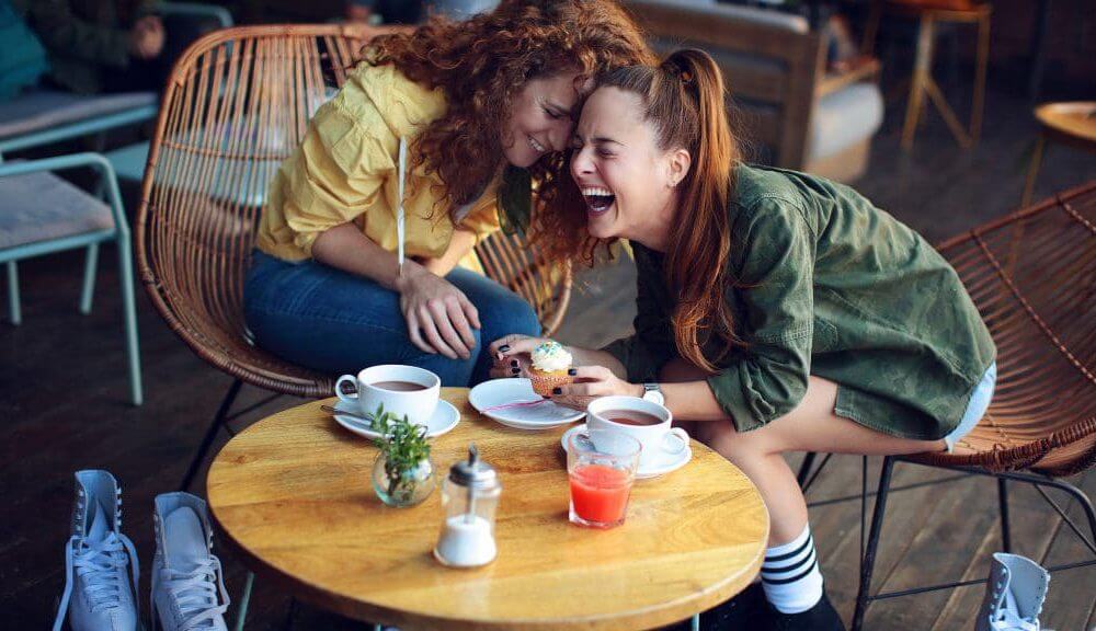 deux femmes en train de boire un café qui rigolent 