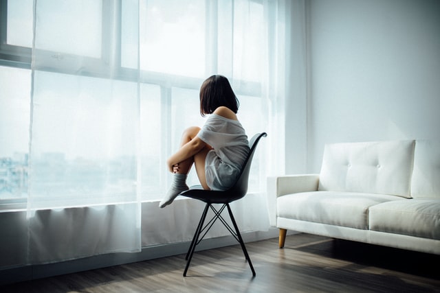 Depressive Frau alleine in einem Zimmer