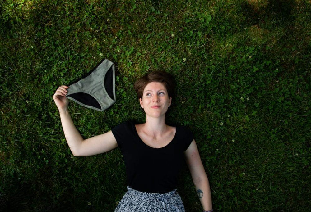 femme couché dans l'herbe avec une culotte menstruelle bon pour le corps et l'écologie