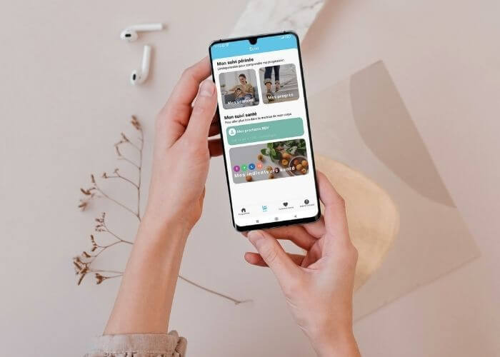 Femme avec Smartphone entre les mais avec l'app Emy pour suivre sa santé et ses mictions.