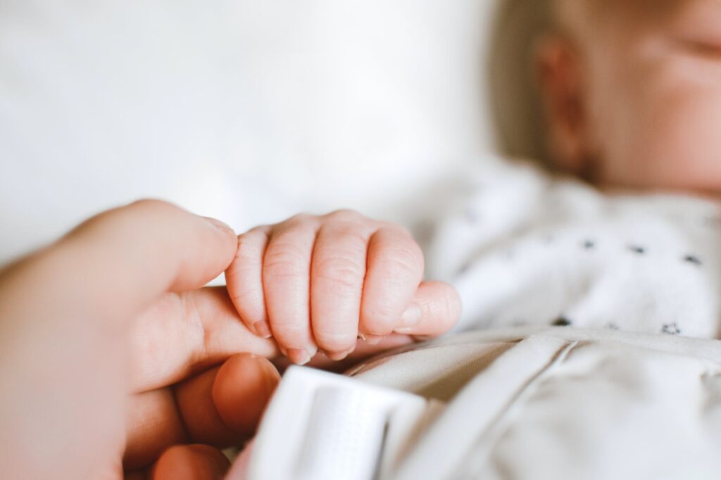 maman qui donne la main à son bébé après son accouchement