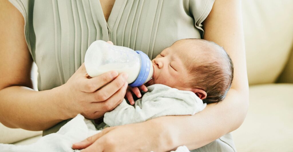 baby drinking from a bottle with his mom