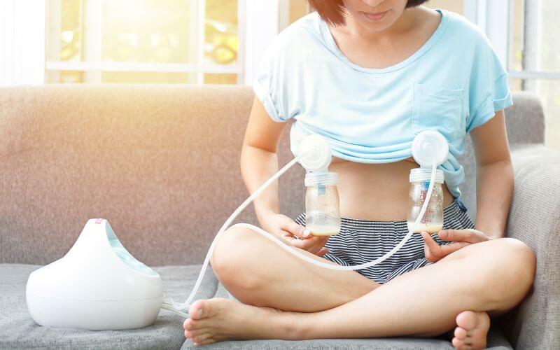 Woman pumping milk with electric breast pump in a cumbersome way