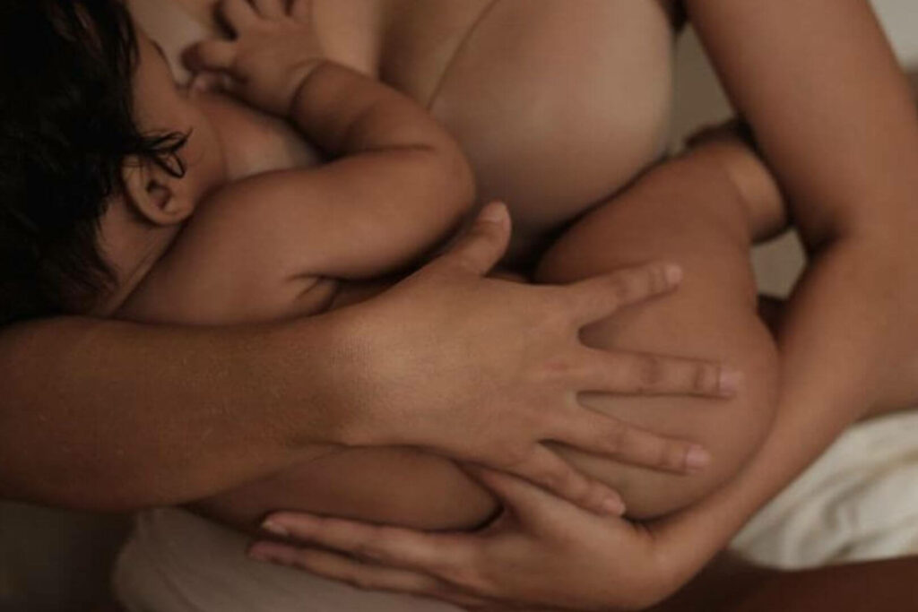 Baby liegt im Arm der Mutter und wird gestillt